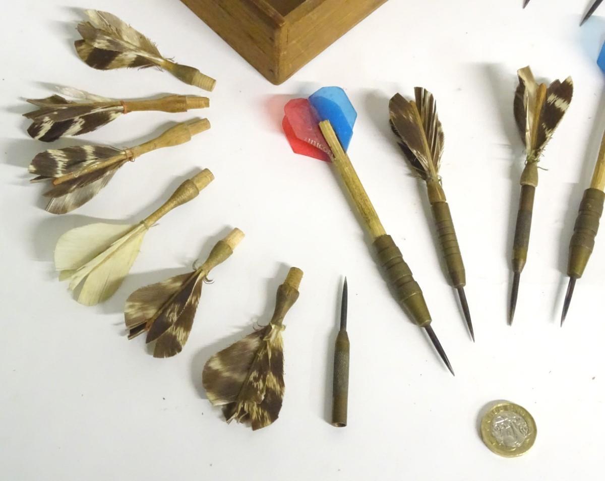 A box of vintage darts some with feather flights contained within a wooden box. Approx. 7 pieces.