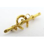 A 9ct gold brooch with horseshoe and riding whip decoration. 1 1/4" long Please Note - we do not