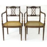 A pair of early 20thC mahogany open armchairs with caned seats, pierced and carved top rail and back