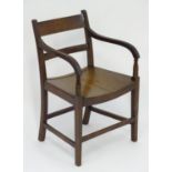 An early 19thC mahogany open armchair with shaped arms and reeded supports above squared tapering