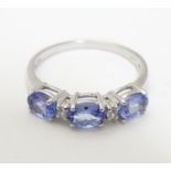 A 9ct white gold ring set with three tanzanite and two diamonds in a linear setting, Ring size