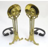 A pair of Art Nouveau andirons, the brass uprights with stylised lotus finials above reticulated