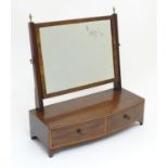 A 19thC mahogany toilet mirror with a rectangular adjustable mirror and mounted by brass finials.