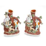 A pair of Staffordshire figural spill vases with a man and woman resting on the branches of a tree