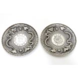 Two white metal dishes with dragon decoration one set with a Republic of China one dollar coin/