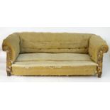 An early 20thC Chesterfield sofa with scrolled arms and standing on turned tapering front legs and