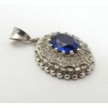 A white gold pendant of oval form set with central sapphire bordered by white stones. Approx 1" long