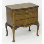 A mid 20thC walnut chest of drawers with a serpentine shaped top above three long graduated