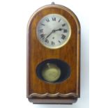 An early to mid 20thC wall clock, the arch top mahogany case with glazed sections, the 7" metal