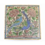 A Persian tile of square form decorated with stylised birds, flowers and foliage within a blue