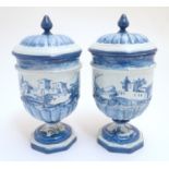 A pair of Continental blue and white pedestal jars and covers decorated with hand painted