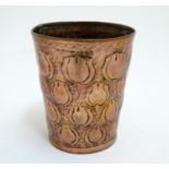 An Arts and Crafts copper beaker of tapering form with repousse floral decoration in the manner of