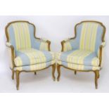A pair of 20thC satinwood armchairs with shaped backrests, carved arms and standing on scrolled