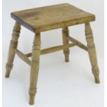 An early 20thC stool with a rectangular top above turned tapering legs united by a H stretcher.