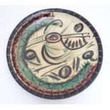A 20thC studio pottery charger with hand painted abstract decoration. Marked to base Manasseh NP