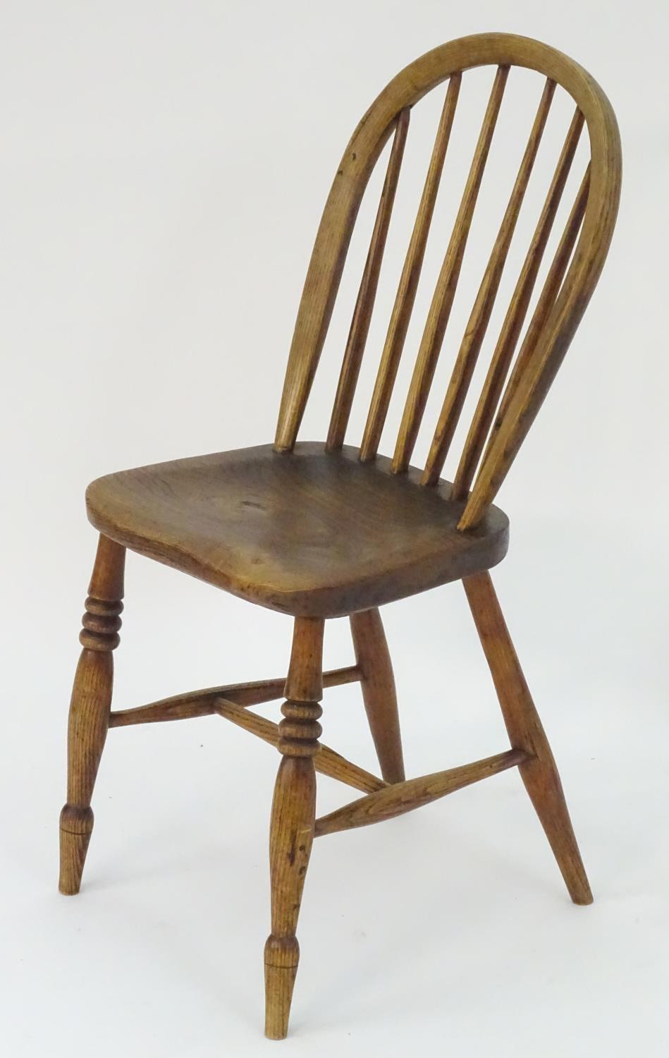 A 19thC elm childs Windsor chair with bowed back and stick supports above a shaped seat and raised