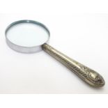 White metal mounted magnifying glass. Glass approx. 2 ½? diameter, approx. 6? long overall. Please
