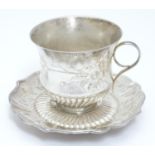 Chinese Export : An Oriental white metal teacup and saucer with engraved floral and bird