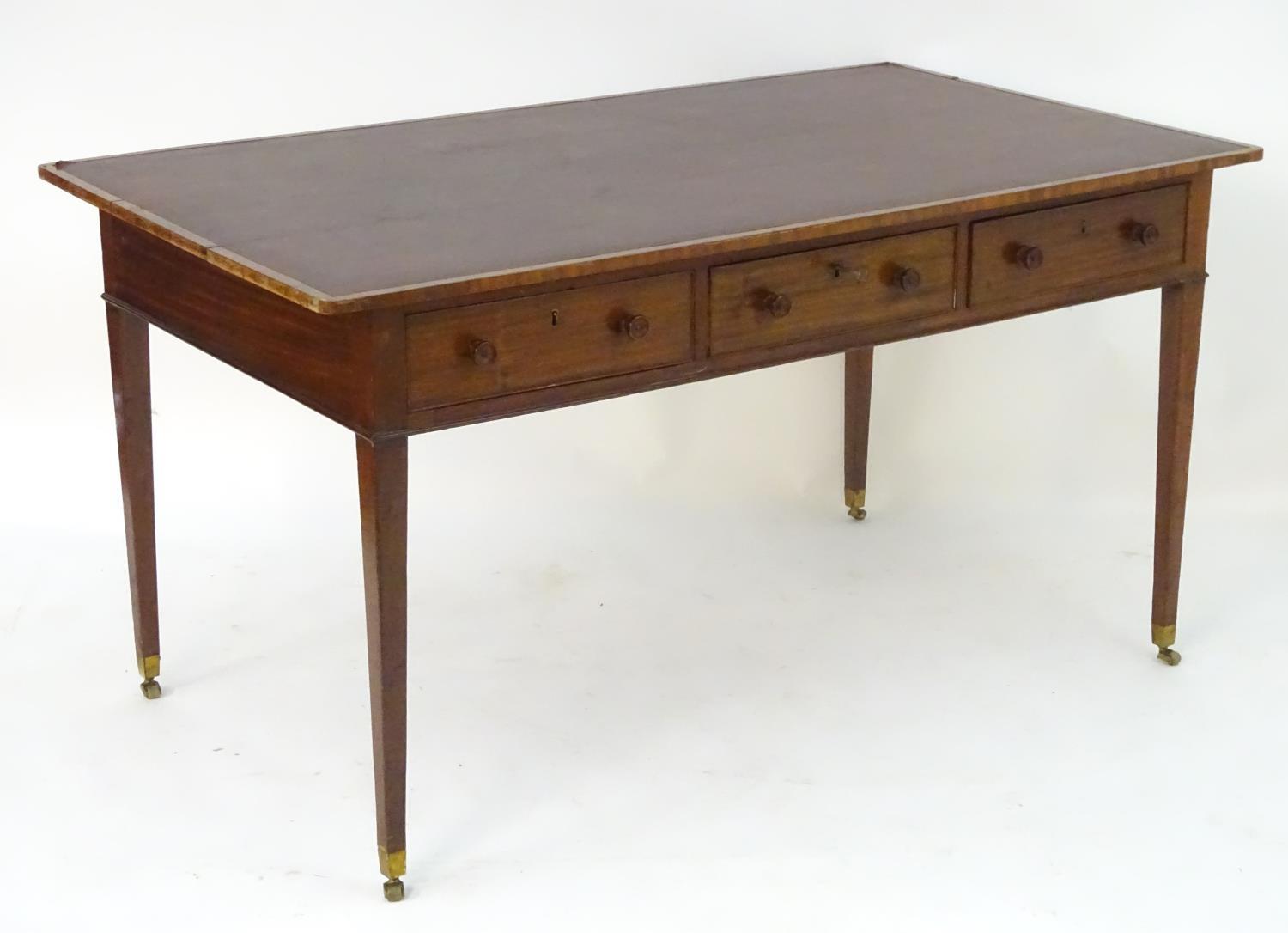 A late 18thC / early 19thC mahogany writing table with an inset top above three short drawers and