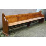 A mid / late 19thC pine pew with scrolled ends, panelled back and full length stretcher. 132"long