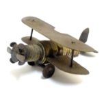 A folkart / trenchart model of a biplane, of brass construction with a spark plug forming the