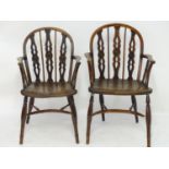 A pair of late 18thC yew wood Windsor chairs with draught back supports and shaped arms, the