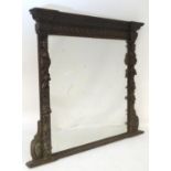 A late 19thC carved oak mirror with an ornately carved frame depicting foliage, fruit, caryatids and
