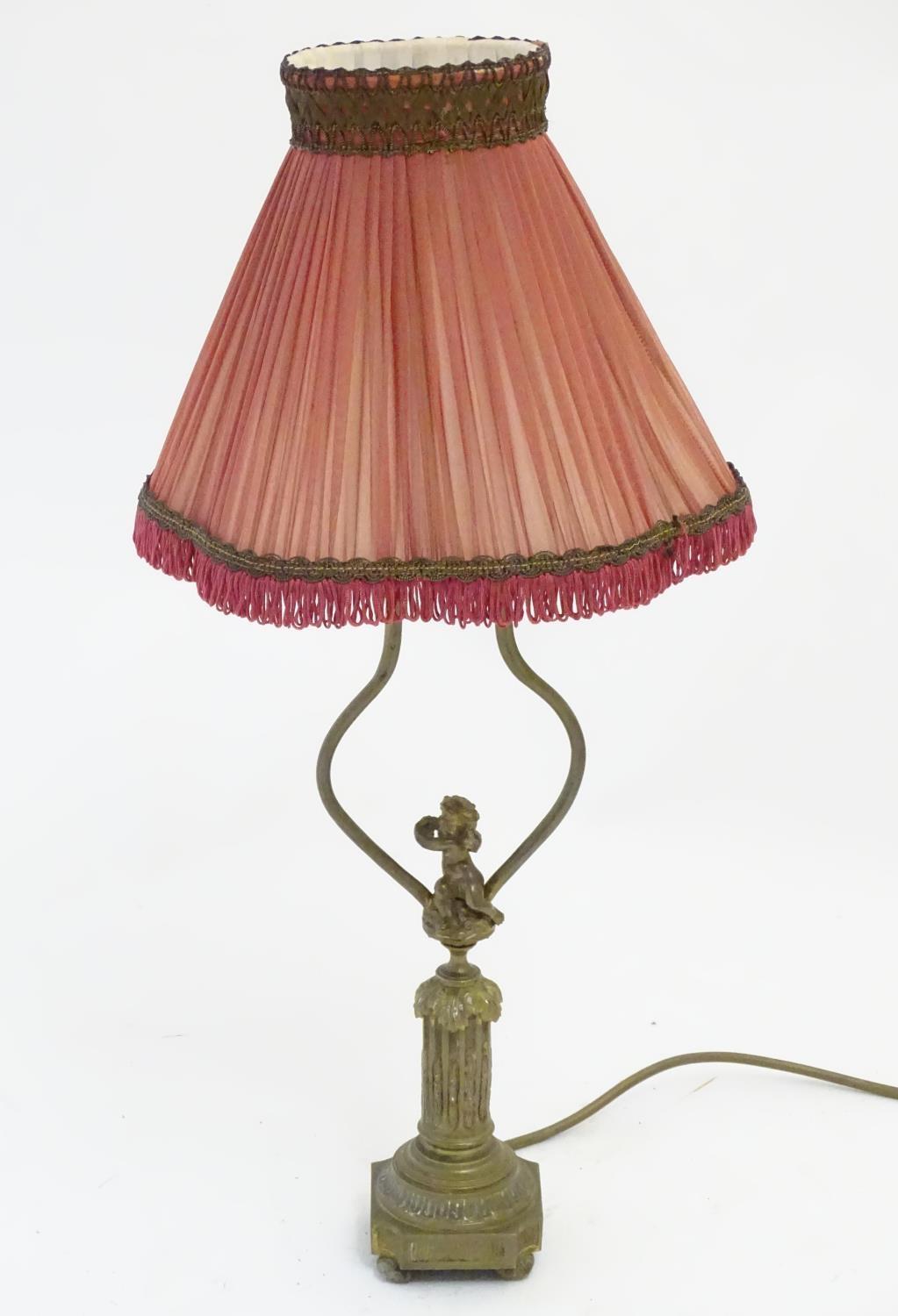 A mid to late 20thC brass table lamp, formed as a Corinthian column surmounted by a putto. 22"