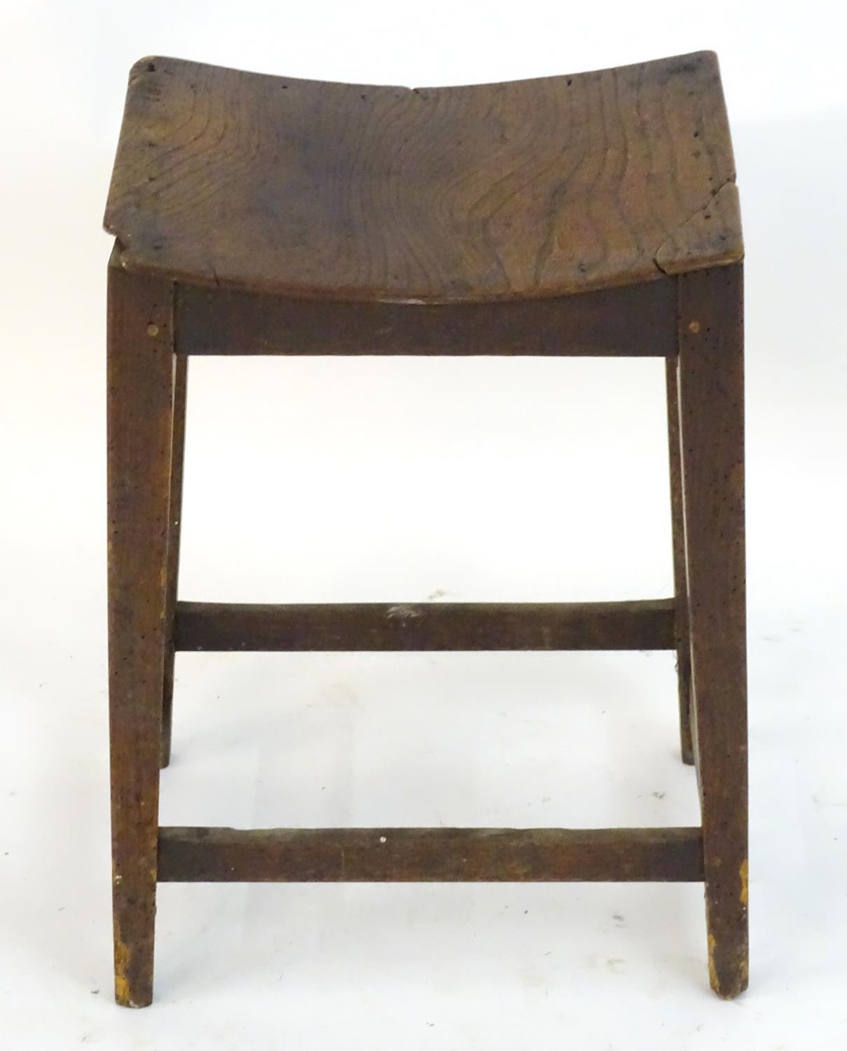 An 18thC elm stool with a bowed top above squared tapering legs and united by a box stretcher. 14? - Image 2 of 4