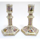A pair of Berlin porcelain candlesticks on hexagonal bases with gilt and floral detail and hand