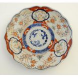 An Imari style plate with a lobed rim, decorated with floral and foliate scenes with panelled