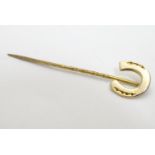 A yellow metal stick / stock pin surmounted by a horseshoe 2"long Please Note - we do not make