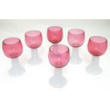 A set of six early 20thC cranberry hock glasses with ribbed milk glass stem bases, each 5 1/4"