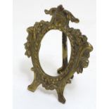 A late 19th /early 20thC cast brass easel back oval frame with floral and scroll detail,