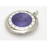 A silver compact with purple guilloche enamel decoration to lid bordered by white enamel. Hallmarked