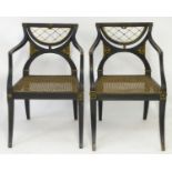 A pair of ebonised Regency open armchairs with gilt and brass detailing above a caned seat, the