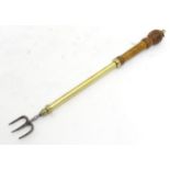 A 19thC toasting fork, with turned walnut handle, telescopic brass stem and cast steel tines,