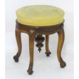 A late 19thc walnut adjustable piano stool, with a rotating upholstered seat above a carved frame