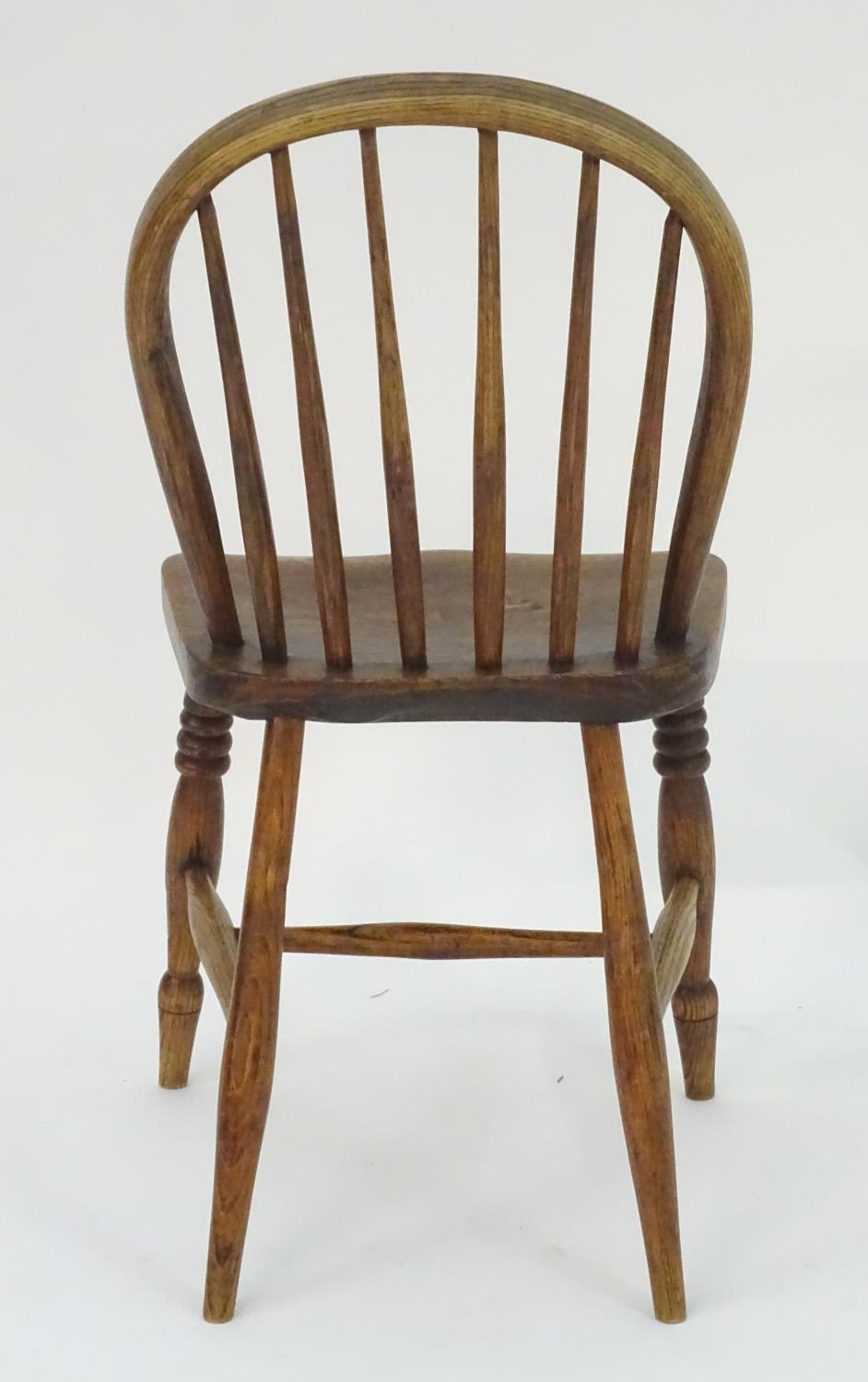 A 19thC elm childs Windsor chair with bowed back and stick supports above a shaped seat and raised - Image 4 of 4