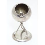 A novelty silver plate ashtray formed as a hockey ball supported on a base formed as three hockey
