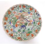 A Chinese plate with a lobed rim and hand painted famille verte decoration, the central section with