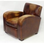 An early / mid 20thC Art Deco club armchair with leather upholstery and raised on squared feet.