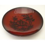 A Royal Doulton flambe dish depicting a wooded landscape with a classical ruin. Marked under Woodcut