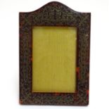 A 19thC wooden easel back photograph frame with tortoiseshell surround having scrolling white