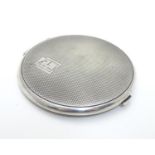 An Art Deco silver powder compact with engine turned decoration. Hallmarked Birmingham 1938 maker