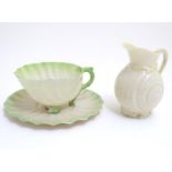 A Belleek tea cup and saucer of shell form with green highlights. Together with a Belleek jug, the