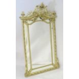 A large early 20thC mirror with a carved top depicting cherubs among foliage flanked by carved
