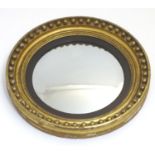 A 19thC convex mirror with an ebonised surround and a moulded frame having applied bauble decoration