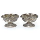 A pair of Victorian silver table salts with fluted decoration and wavy rims, raised on oval pedestal