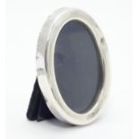 A photograph frame of oval form with silver surround hallmarked Sheffield 1927. Approx 3" high